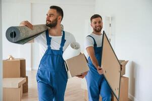 Mat and painting in, hands. Two moving service employees in a room photo