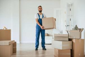 Full height ,,photo, standing and holding big box. Moving service employee in a room photo