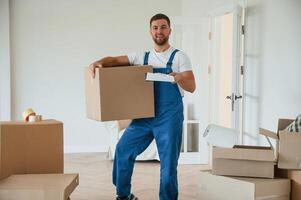 Looking, at the camera, holding box. Moving service employee in a room photo