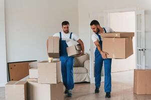 Front view, holding, stuff. Two moving service employees in a room photo