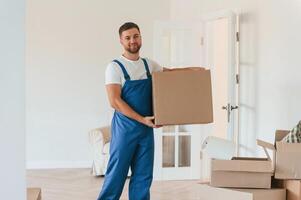 Looking,, at the camera, holding box. Moving service employee in a room photo