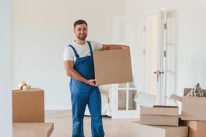 Looking ,at the camera, holding box. Moving service employee in a room photo