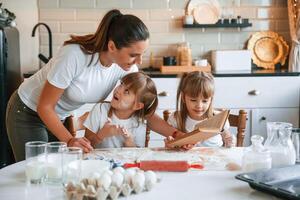 Natural, ingredients.. Mother with her little two daughters is preparing food on the kitchen with garlands together photo