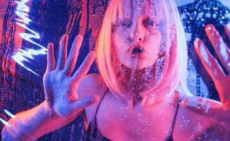 Hands ,are on the, surface. Stylish woman with white hair is behind wet transparent plastic sheet photo
