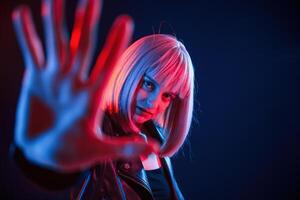 Hand in front of her. Woman with ,white ,hair is in studio with neon colors photo