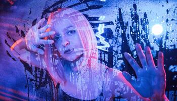 Hands are ,on the ,surface. Stylish woman with white hair is behind wet transparent plastic sheet photo