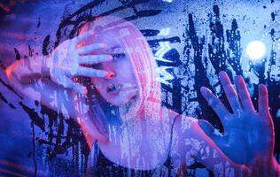 Hands, are on the ,surface. Stylish woman with white hair is behind wet transparent plastic sheet photo