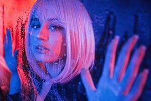 Front view. Stylish woman with, white, hair is behind wet transparent plastic sheet photo