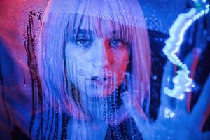 Front view. Stylish woman ,with white hair is behind wet transparent plastic sheet photo