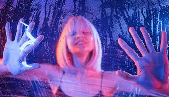 Trapped, inside, with hands on surface.. Stylish woman with white hair is behind wet transparent plastic sheet photo