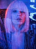 Front view. ..Stylish woman with white hair is behind wet transparent plastic sheet photo