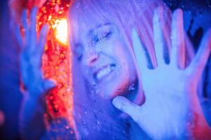 Hands, are on the surface. Stylish woman with white hair is behind wet transparent plastic sheet photo