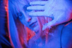 Blue ,color in the front and red is behind. Stylish woman with white hair is behind wet transparent plastic sheet photo