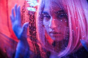 Front view... Stylish woman with white hair is behind wet transparent plastic sheet photo
