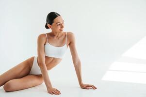 Posing for the, camera. Woman, in, white underwear with slim body type against white background photo
