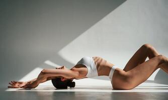 Shadows and sunlight. Doing ,,exercises. Woman in white underwear with slim body type photo