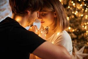 Closeness, of, the people. Beautiful young couple indoors, celebrating new year against projector photo