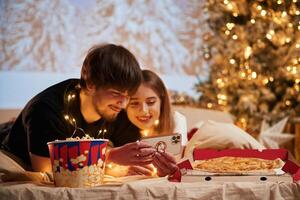 Taking, photo by phone. Beautiful young couple indoors, celebrating new year against projector