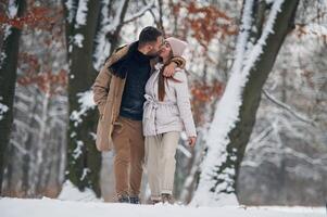 Lovely couple have a walk in the winter forest photo