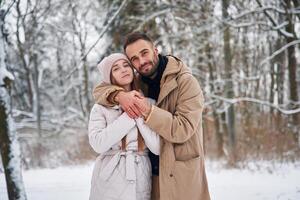 Cheerful, facial, expression. Lovely couple have a walk in the winter forest photo