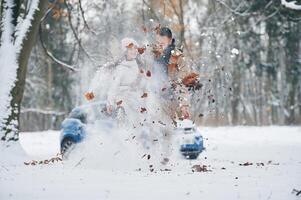 Front ,view,, having fun. Happy couple having a walk in winter forest. Blue car is parked photo