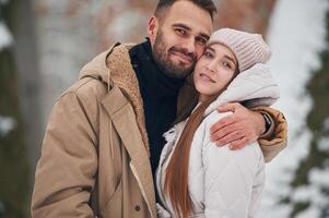 Cheerful facial expression,. Lovely couple have a walk in the winter forest photo