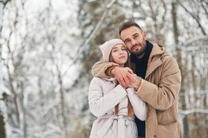 Cheerful facial ,expression. Lovely couple have a walk in the winter forest photo