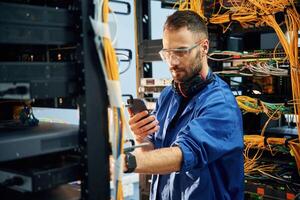 Restoring the internet connection.., Young man is working with equipment and wires in server room photo