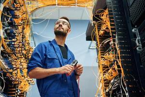 Handsome young man, is working, with internet equipment and wires in server room photo