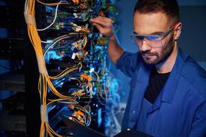 In glasses., Young ,,man is working with internet equipment and wires in server room photo
