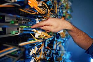 Cables management. Young man is working with internet equipment and wires in server room photo