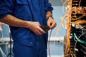 Cutting the wire., Young man is working with internet equipment in server room photo