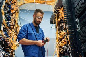 Handsome young, man ,is working with internet equipment and wires in server room photo