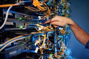 Cables ,,management. Young man is working with internet equipment and wires in server room photo