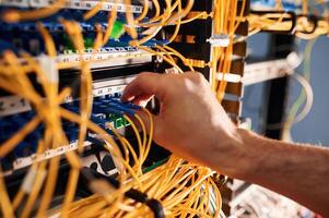 Close ,up view of hand that fixing ,internet. Young man is working with equipment and wires in server room photo