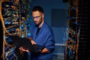 Repairman is busy ,and working with internet equipment and wires in server room photo