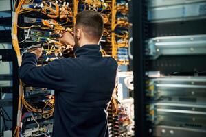 Young man is working with internet ,equipment and wires in server room photo