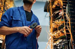 Repairman is, busy, and working with internet equipment and wires in server room photo