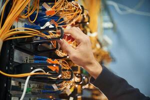 Young man ,is ,working with internet equipment and wires in server room photo
