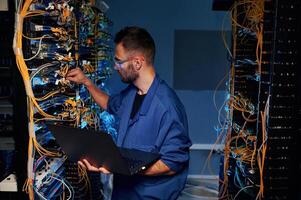 Repairman is busy and, working with internet equipment and wires in server room photo