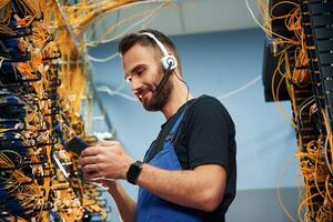 Young man is working ,with internet equipment and wires in server room photo