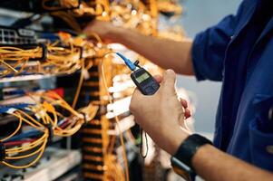 Signal ,stability, measured by device. Young man is working with internet equipment and wires in server room photo