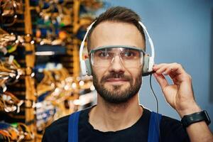 In headphones... Young man is working with internet equipment and wires in server room photo