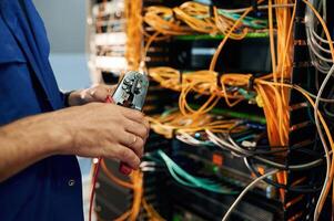 Close ,up, view of hand that fixing internet. Young man is working with equipment and wires in server room photo