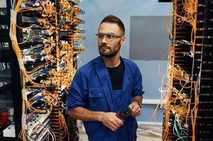 Administrator is ,,busy. Young man is working with internet equipment and wires in server room photo