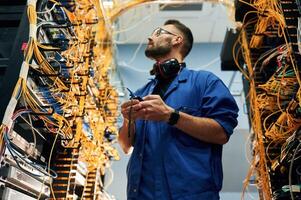View from, below. Young man is working with internet equipment and wires in server room photo