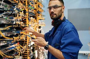 Signa,l stability measured by device. Young man is working with internet equipment and wires in server room photo