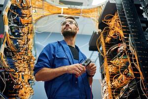 Cutting,, the wire. Young man is working with internet equipment in server room photo