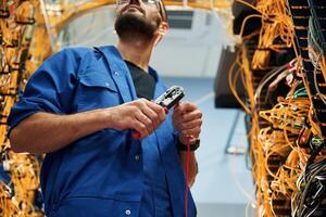 Busy,, by cutting the wire. Young man is working with internet equipment in server room photo