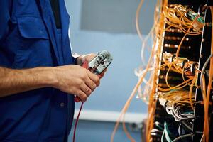 Cutting, the wire. Young man is working with internet equipment in server room photo